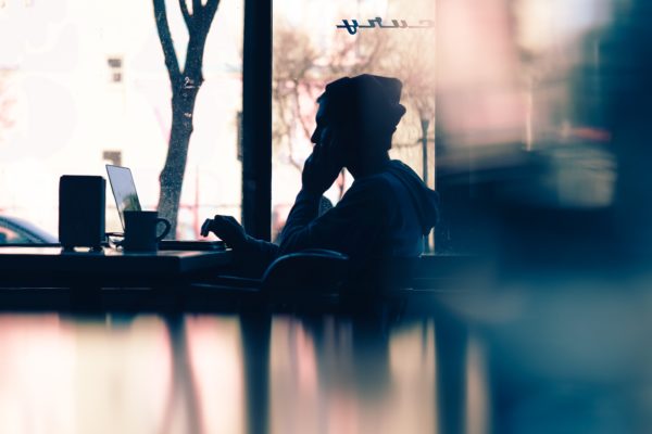 Image of a lone figure embracing their laptop lifestyle by working on their laptop in a cafe type setting.