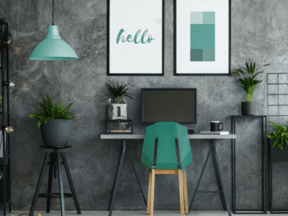 Image of a virtual office space with laptop, green chair, green lamp and desk with a grey wallpaper as a background.